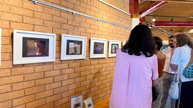 Visitors stand in front of framed photographs on the brick wall of the gallery.