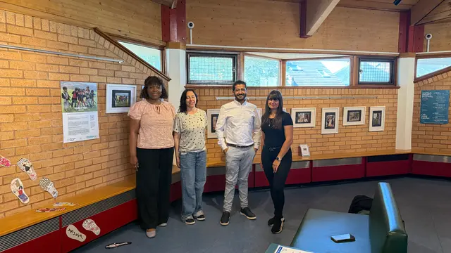 Four people stand together in front of the framed photographs in the gallery.