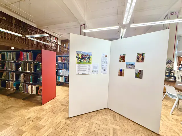 Display walls with photographs and an information panel among library bookshelves.