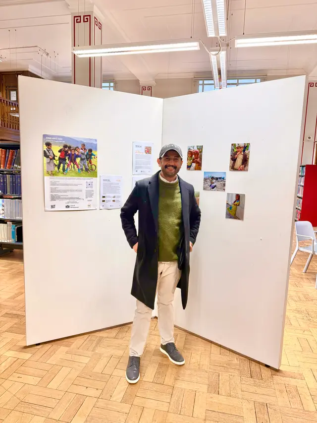 A man stands between two display walls of photographs and an information panel.